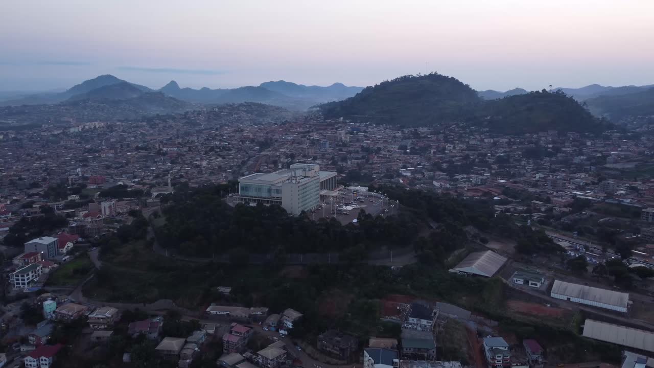 Inquadratura di apertura della Sala del Congresso con le colline di Yaoundé sullo sfondo