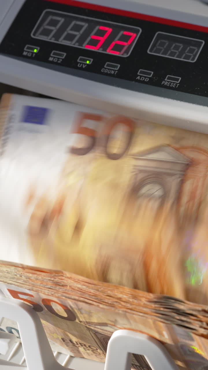 Electronic cash counting machine counts fifty euro banknotes. Figures changing quickly on the counter display at backdrop in blur. Close up. Vertical video