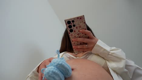 pregnant woman taking a picture of her belly with the smartphone. low angle shot