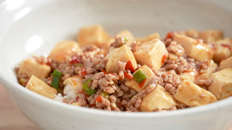 Making-stir-fried-mapo-tofu-with-hot-spicy-sauce-and-scallion-over-white-rice-in-a-bowl-at-home