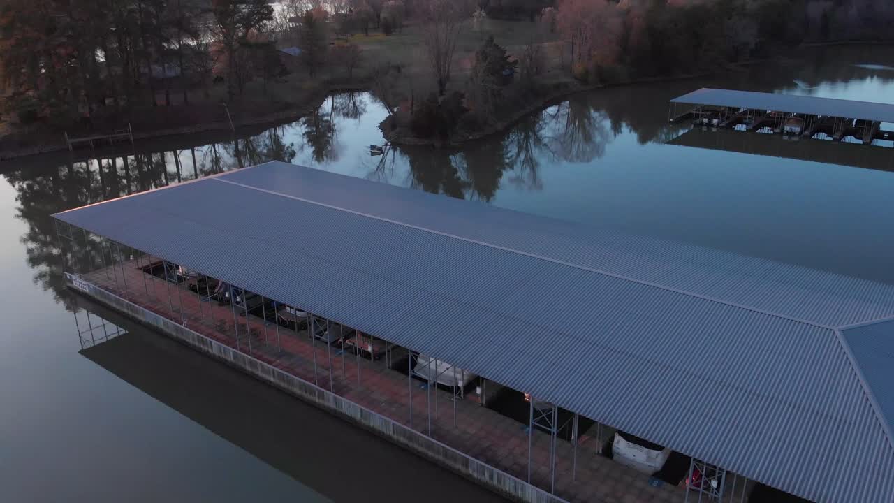 imágenes aéreas volando sobre muelles de barcos hacia tierra al atardecer con reflejos en las aguas tranquilas