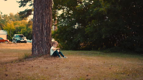 young-girl-eats-yogurt-with-large-spoon-sitting-at-tree