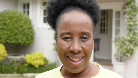 Happy-african-american-senior-woman-with-curly-hair-smiling-in-sunny-garden,-slow-motion