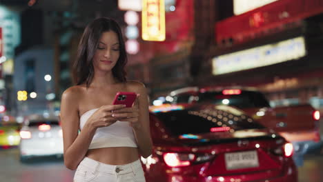 woman using phone in a city street at night