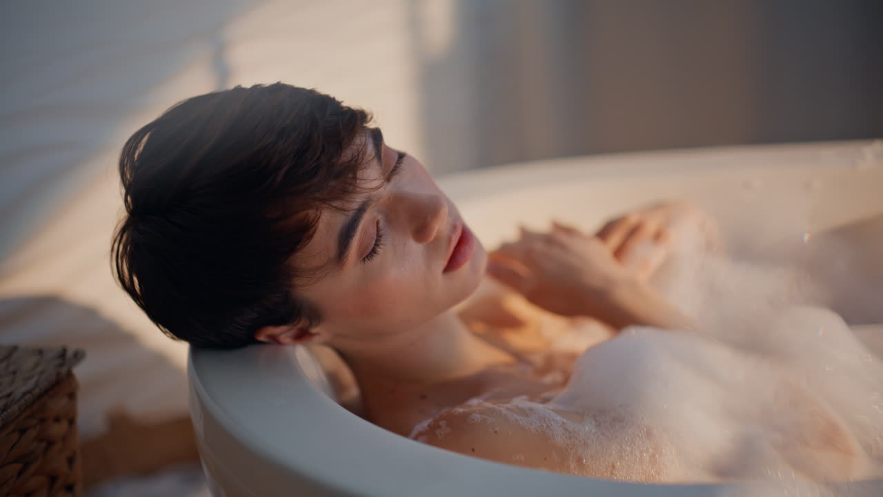 Luxury woman taking bath white foam in home bathroom portrait. Calm girl soaking