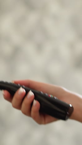 la mujer usa el televisor para correr remotamente por la pared de la habitación en primer plano. la mujer fuerte ve programas de televisión haciendo ejercicio en la cinta de correr en el interior. la deportista se ocupa del aburrimiento en el entrenamiento