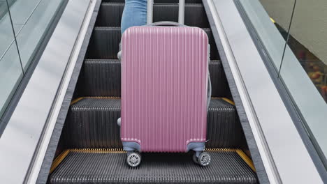 woman with pink suitcase on escalator