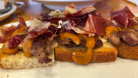 Traditional-Spanish-sandwich-with-Iberico-pork-and-Iberico-ham-with-an-orange-sauce,-tapas-in-Marbella-Spain,-tasty-starter,-4K-shot