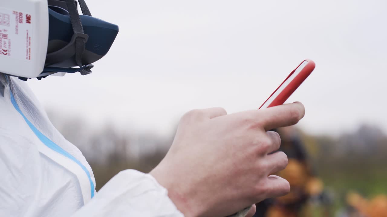 persona con equipo de protección que utiliza un teléfono inteligente