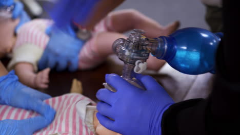 breathing session on a doll. hands in medical gloves doing chest compression on a baby mannequin. training cpr procedure in rescue center. close-up.