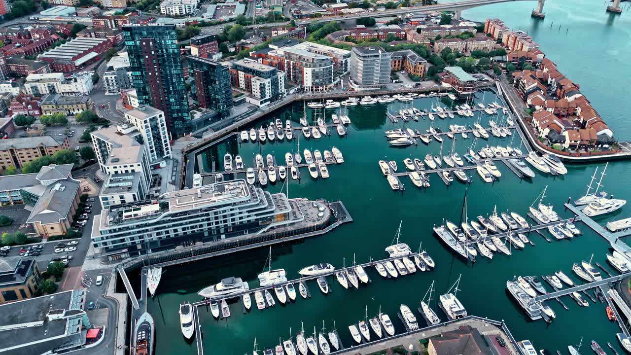 Aerial drone footage of Ocean Village marina in Southampton, showcasing boats, docks, buildings, and waterfront real estate under soft daylight at sunset shot during autumn
