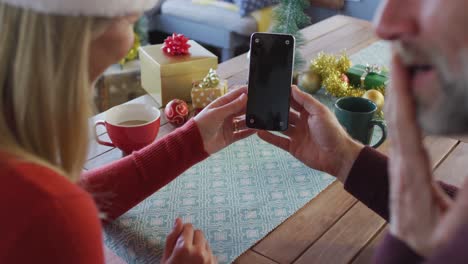 Feliz-Pareja-Madura-Caucásica-Usando-Gorros-De-Papá-Noel-Usando-Un-Teléfono-Inteligente-Con-Espacio-Para-Copiar