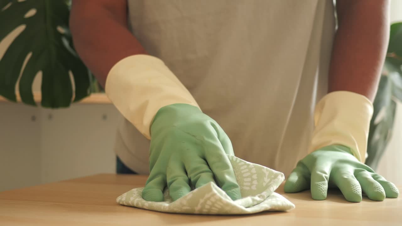 Person in gloves cleaning a table surface