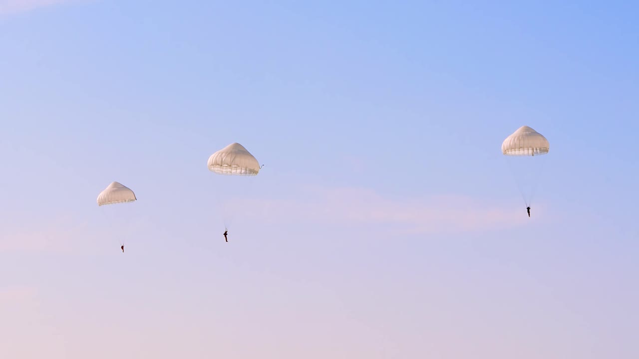 Three Paratroopers Descending Under White Parachutes