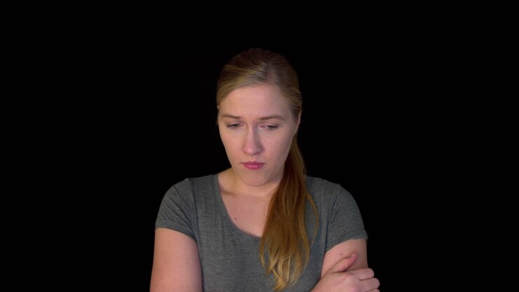 Sad woman stands on black background in slowmotion