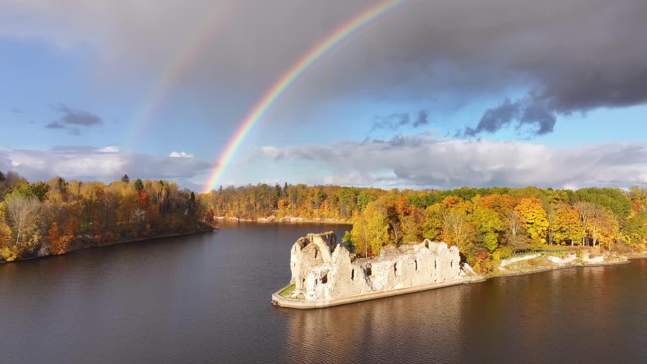 The medieval castle ruins of Koknese in Latvia with a double rainbow in the background on a beautiful autumn day