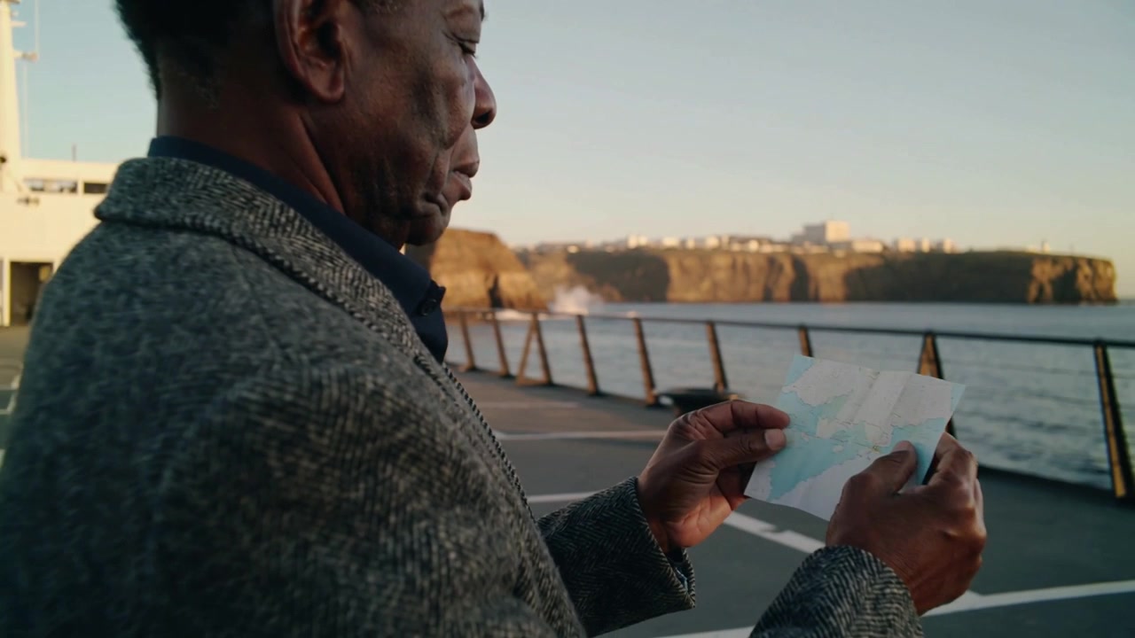Holding map, man in grey coat unfolding, studying it on ferry deck, seeking route, copy space