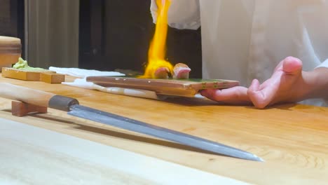 el chef usa una antorcha para preparar el plato de sushi.