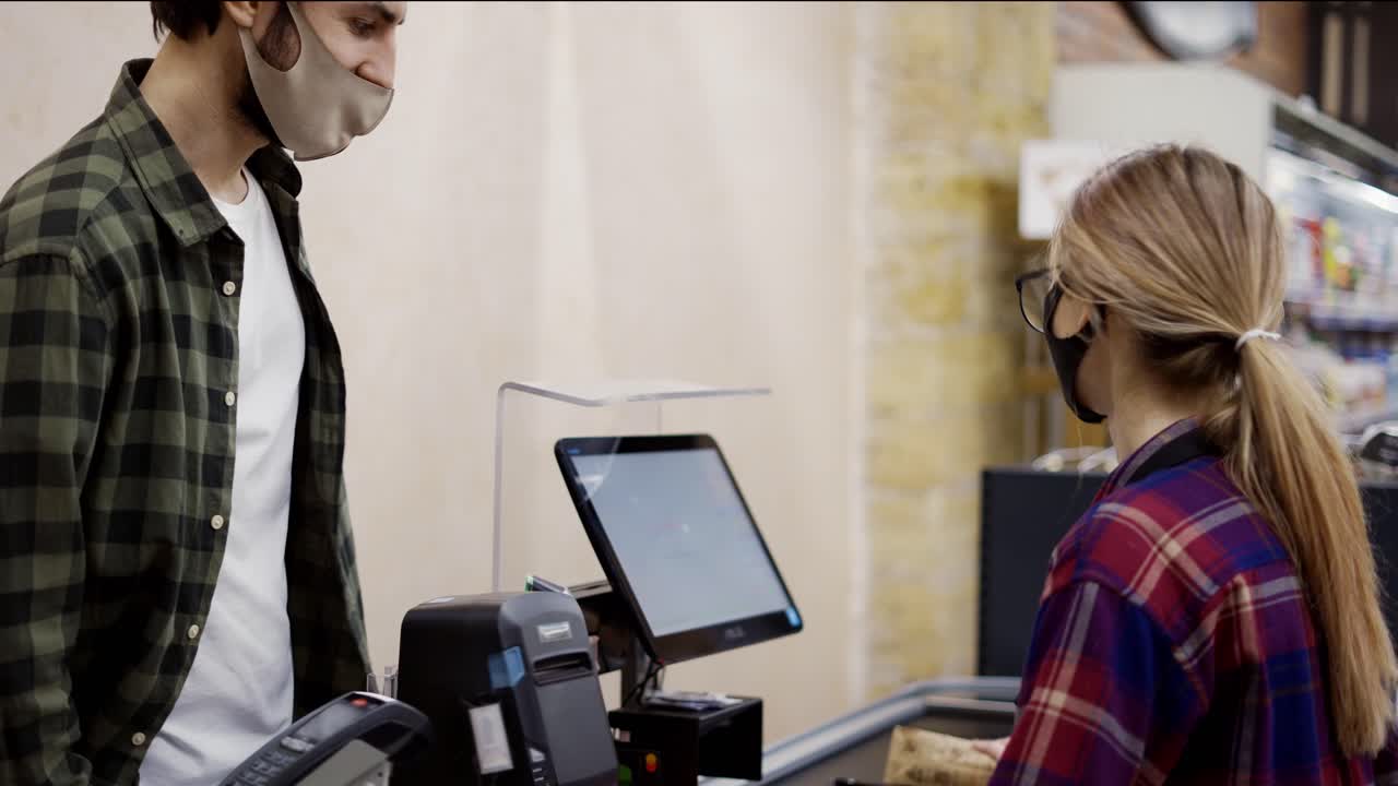 el cliente del mostrador de caja paga con el teléfono inteligente por sus alimentos en el supermercado