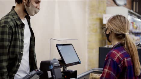 checkout counter customer pays with smartphone for his food items in supermarket