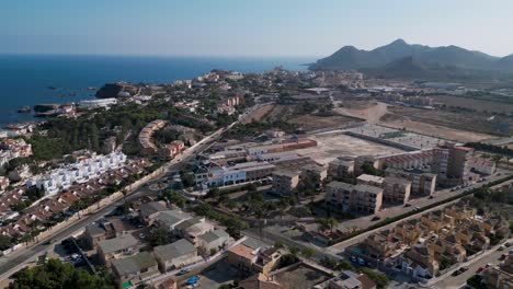 wide orbit aerial view of cabo de palos town or cape palos during a summer day in a small peninsula in the municipality of cartagena, murcia region - mountains and mediterranean sea in the background.