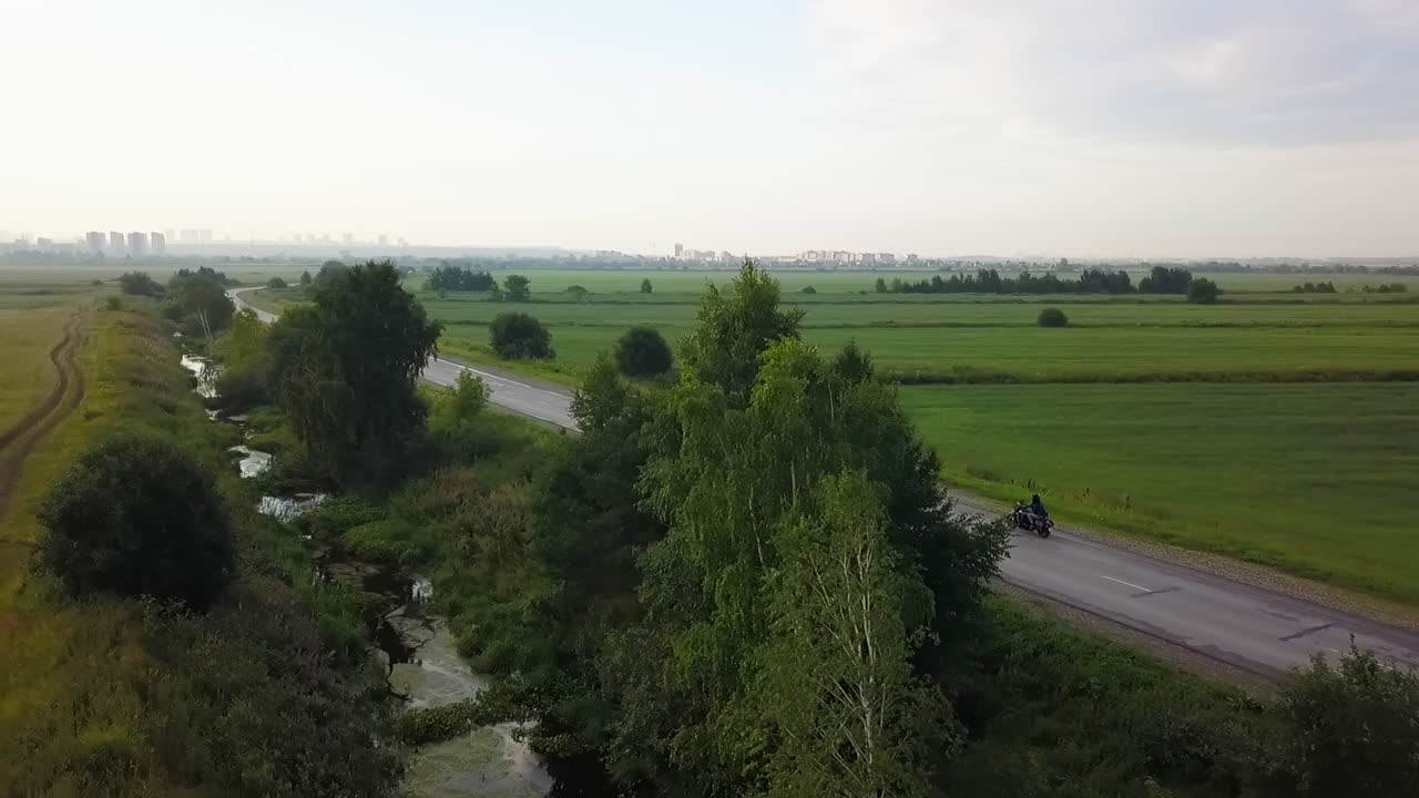Rural Landscape with Road, Stream, and Distant Cityscape