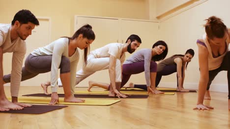 Trainer-assisting-group-of-people-with-stretching-exercise-