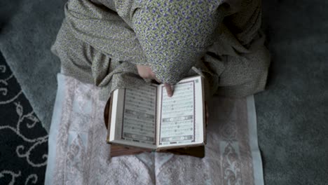 overhead view of person reading quran on a rug, intimate and spiritual atmosphere, close-up