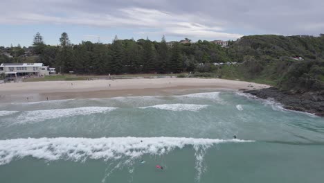 Surfers-In-Flynns-Beach-On-A-Cloudy-Day-In-Port-Macquarie,-Australia---aerial-drone-shot