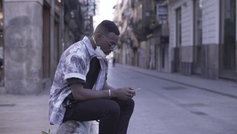man sitting and using smartphone in city street