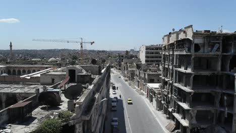 streets of a syrian city with cars and people walking. some of the buildings are still in ruins after the civil war 10 years ago - aerial view 4k