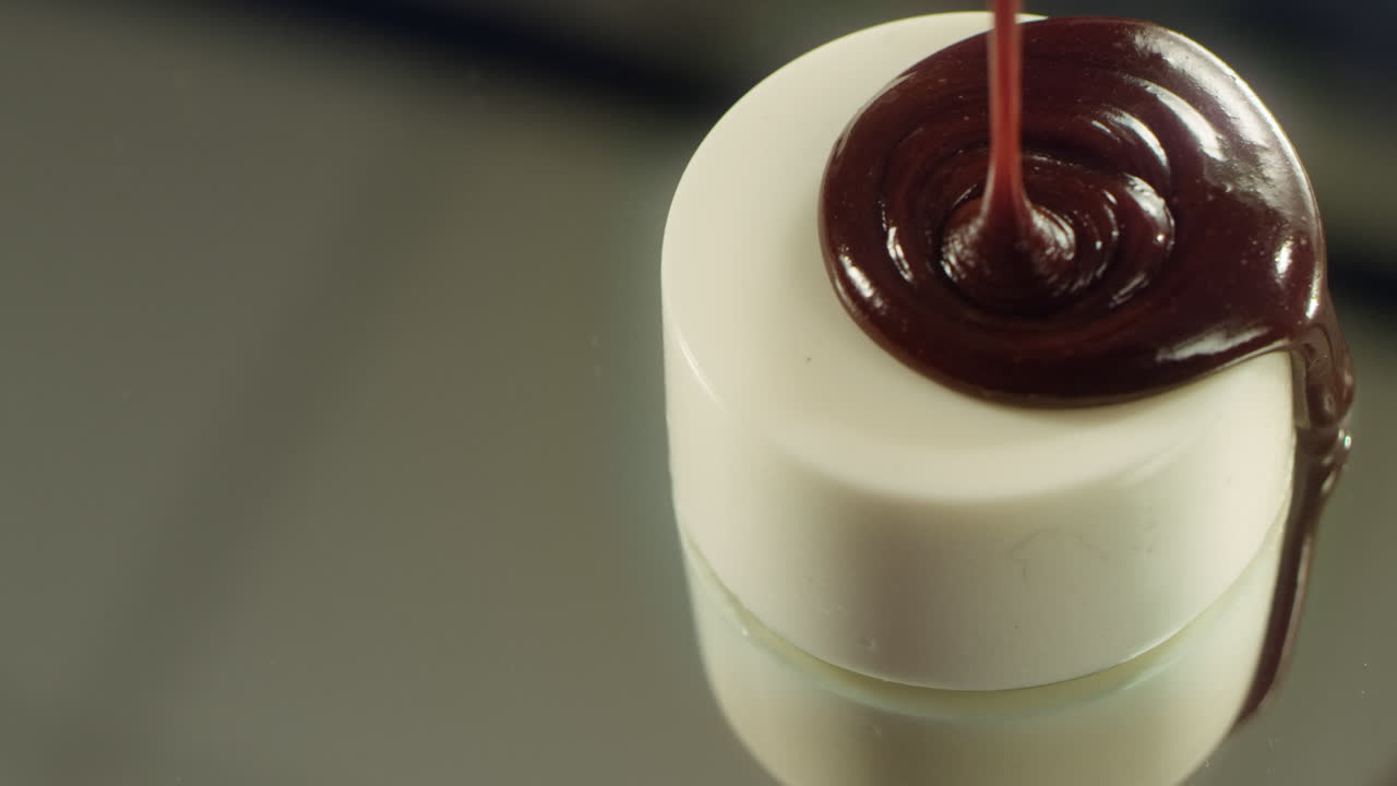 Torta gustosa con glassa bianca e cioccolato caldo versato in una cucina professionale