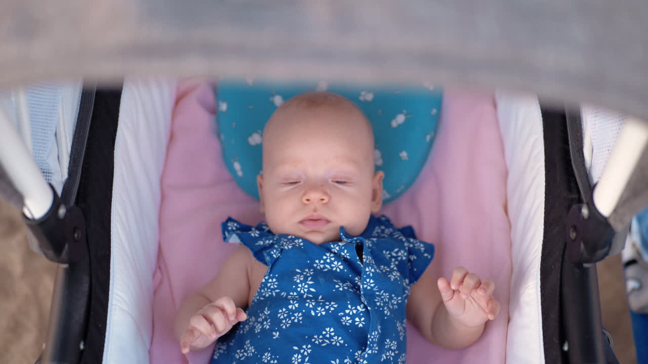 푸른 눈의 귀여운 아기 소녀가 야외에서 pram에
