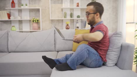 joven con enanismo trabajando en línea desde una computadora portátil en casa, escribiendo texto, haciendo investigación.