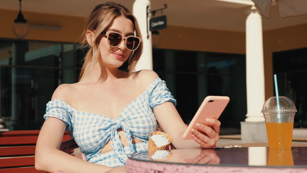 Donna che si gusta un gelato e lo smartphone in un bar