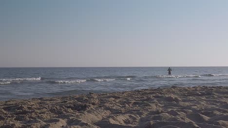 Man-fishing-on-the-ocean-in-the-background,-slightly-out-of-focus