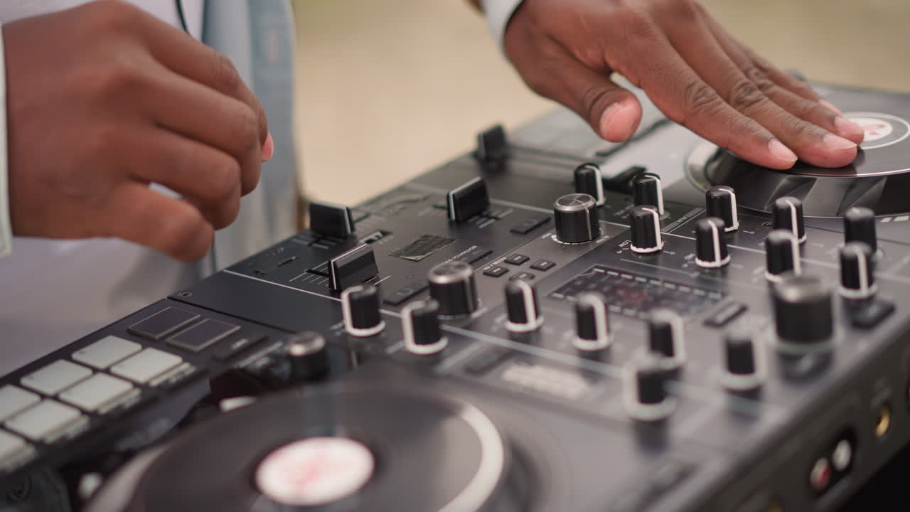 keterampilan mixing DJ ditampilkan di luar, disc jockey kasual menyesuaikan kontrol di lingkungan terbuka, seorang DJ informal dengan terampil me-mix lagu sambil mengelola peralatan di luar ruangan di tengah alam