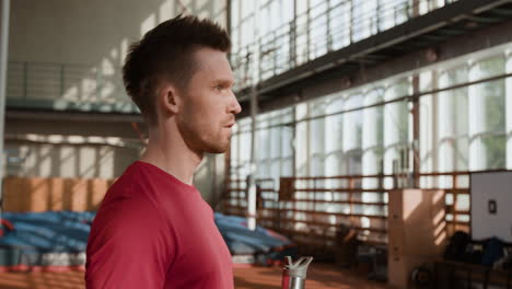man drinks water from a bottle in a gym during a workout