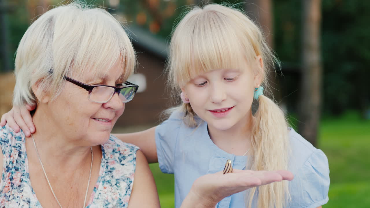 6세 소녀는 손에 있는 작은 달팽이를 본다 - 자연과의 소통