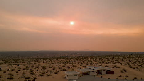 vertical rise drone shot of joshua tree sunset with nearby fire and smoke creating vivid red sky