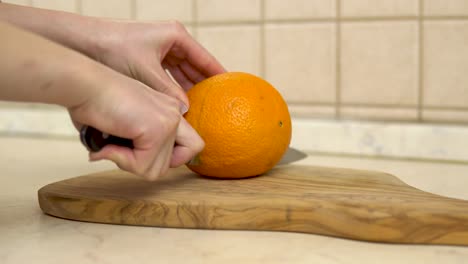 woman cuts an orange in half. woman's hand close up