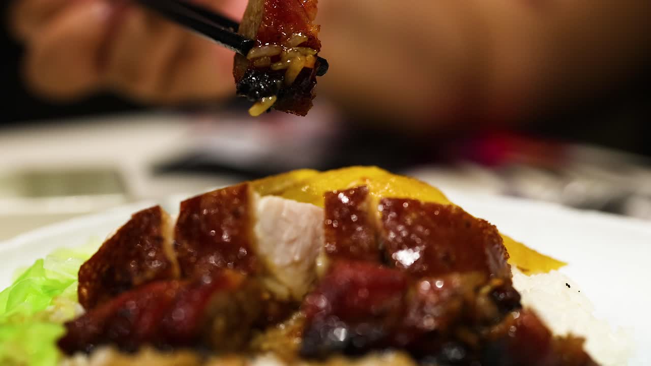Chopsticks lifting roast duck from a plate