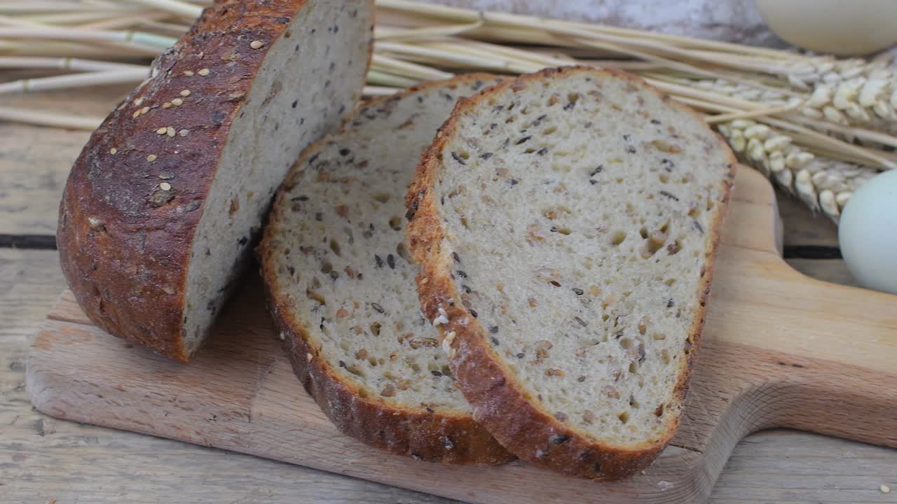 Loafs of bread, slices of bread, wheat flour, eggs and ears of grain on wood background. Rustic and rural concept. Close up. Flat lay
