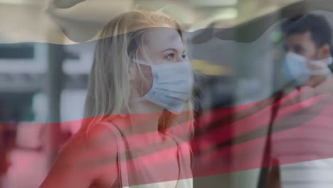 animation of flag of russia waving over woman wearing face mask during covid 19 pandemic