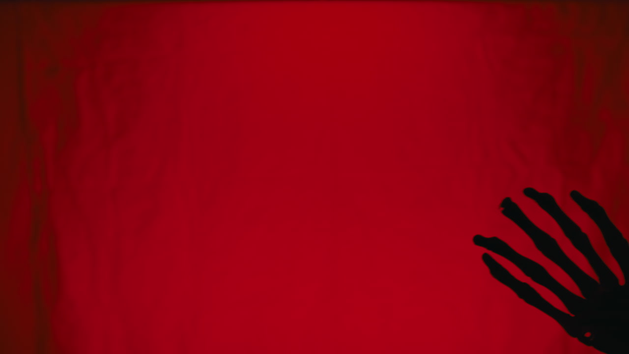 Horror Skeleton Hand Moves in Front of Red Screen for Halloween copy space
