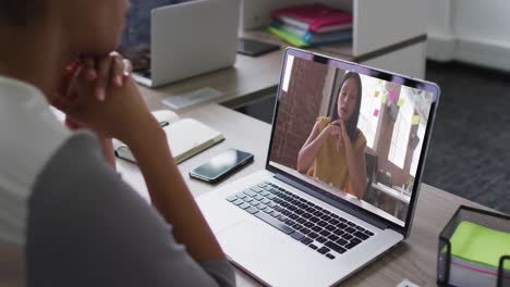 sección media de una mujer afroamericana haciendo una videollamada con una colega en una computadora portátil en la oficina