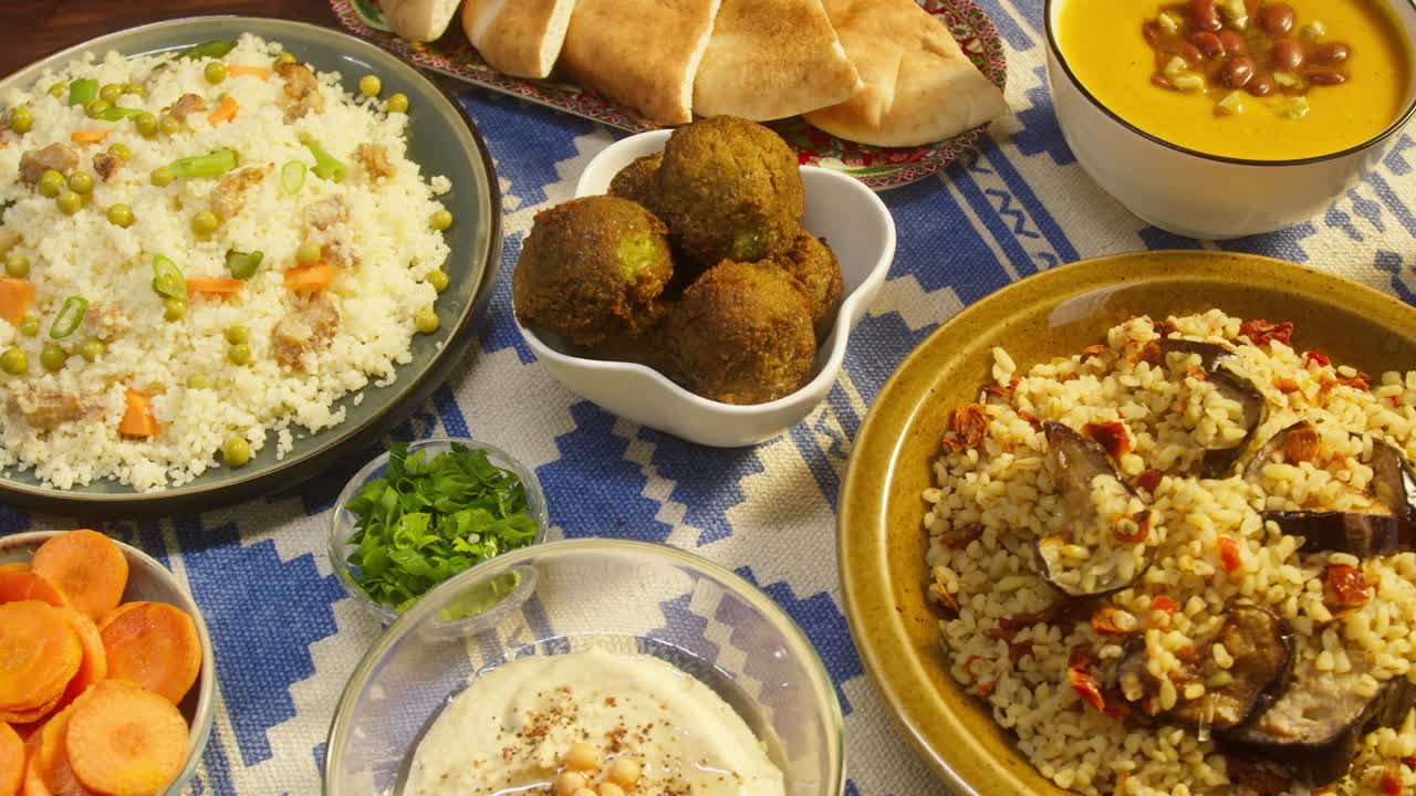 cocina árabe. bulgur con berenjena, falafel, sopa de frijoles en la mesa, cuscús con pollo. cultura tradicional de oriente medio. moutabal y ensalada de verduras en cuencos, pita. arroz delicioso con carne