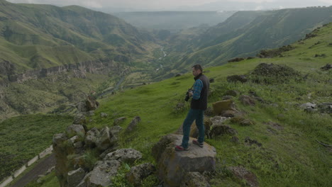 Landscape-Photographer-With-Camera-Standing-On-The-Rock-Taking-Pictures-Of-Mountain-Range-And-Valley-In-Georgia