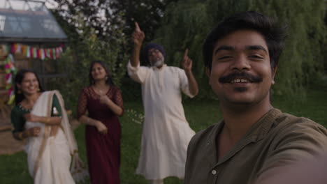 joyful indian family dancing and celebrating outdoors while taking a selfie