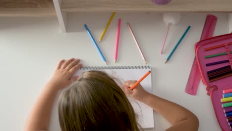 Overhead-of-a-little-girl-at-her-table-drawing